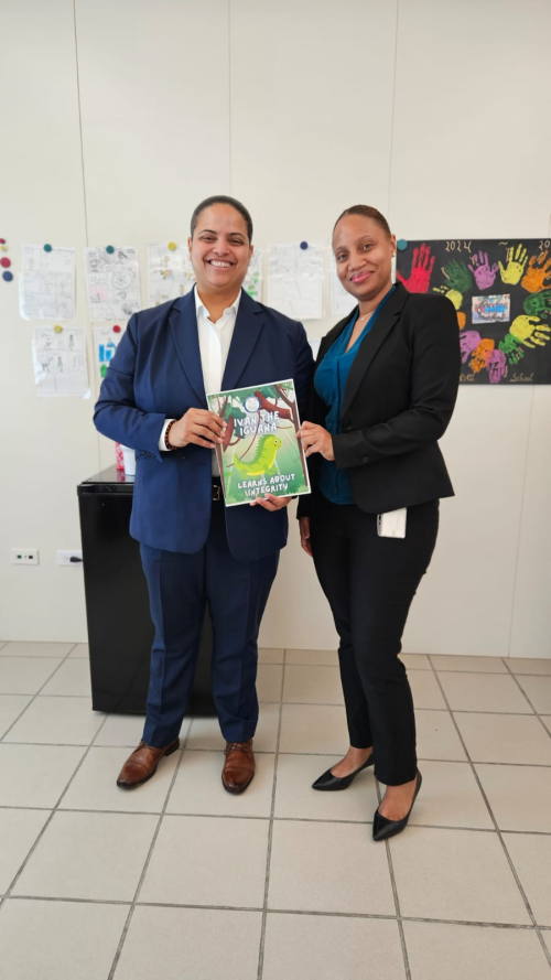 Director of the Integrity Chamber, Charna Pompier presents the Chamber’s ‘Ivan The Iguana’ coloring book to Minister of Education, Melissa Gumbs mellisaintegritybook28102025